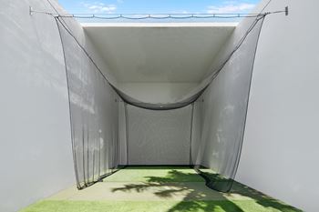 A white tent with a mesh top is set up on a green surface.